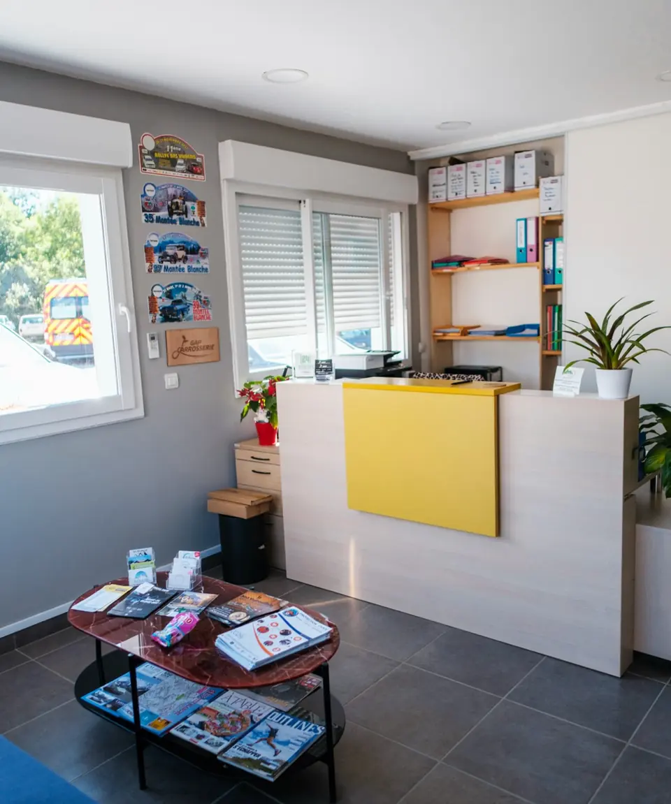 L’accueil de l’atelier : un comptoir jaune, des fauteuils et une table basse
