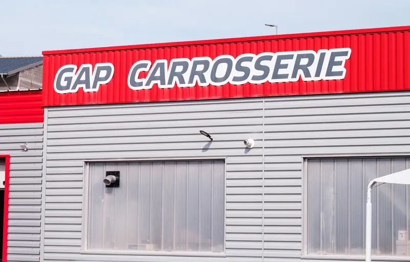 L’enseigne GAP CARROSSERIE sur le bardage rouge de l’atelier