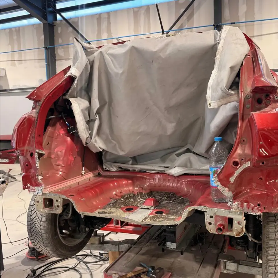 Avant : l’arrière d’un Hyundai Kona rouge arraché, bâché, à l’atelier